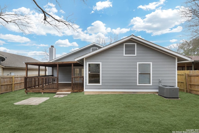 rear view of house with cooling unit, a deck, and a lawn