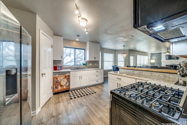 kitchen with ventilation hood, white cabinetry, dishwasher, hanging light fixtures, and light hardwood / wood-style flooring