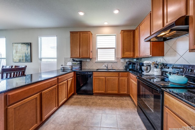 kitchen with sink, dark stone countertops, black appliances, decorative backsplash, and kitchen peninsula