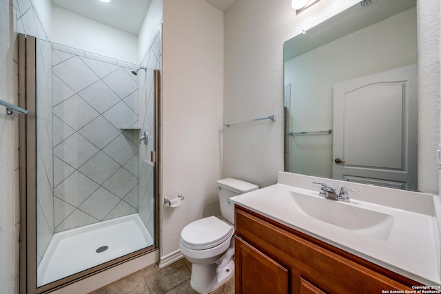 bathroom featuring tile patterned flooring, vanity, a shower with shower door, and toilet