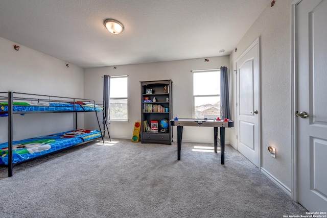 bedroom with multiple windows, a textured ceiling, and carpet flooring