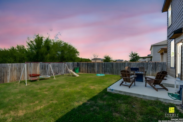 yard at dusk featuring a patio and a playground