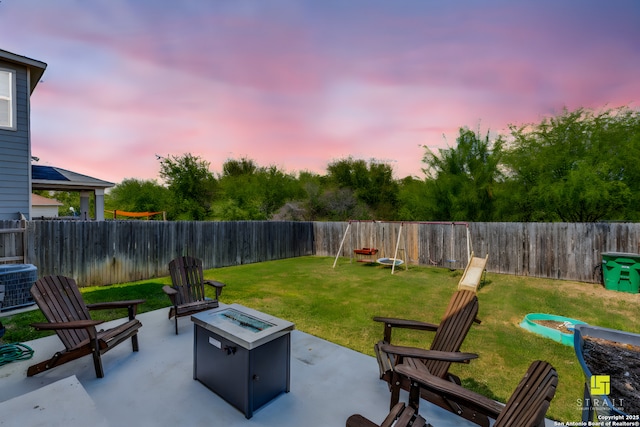 patio terrace at dusk with central AC, a fire pit, and a lawn