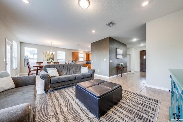 tiled living room featuring a textured ceiling and a chandelier