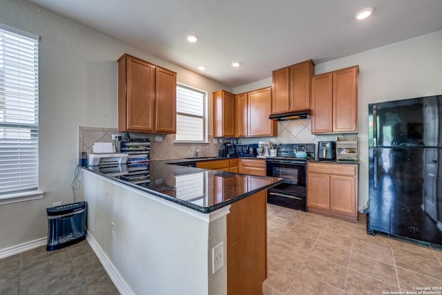 kitchen featuring black appliances, sink, dark stone countertops, decorative backsplash, and kitchen peninsula