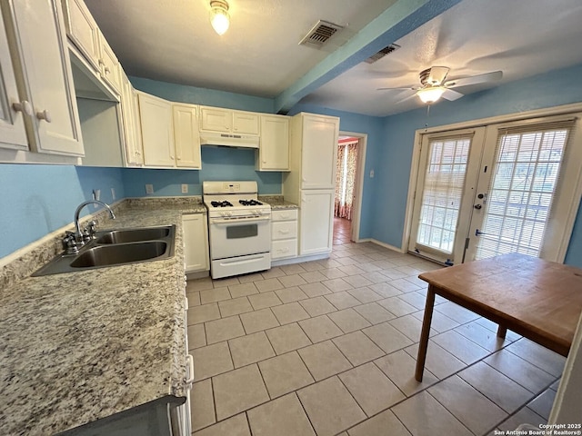 kitchen with sink, white cabinetry, light stone counters, light tile patterned flooring, and white gas range