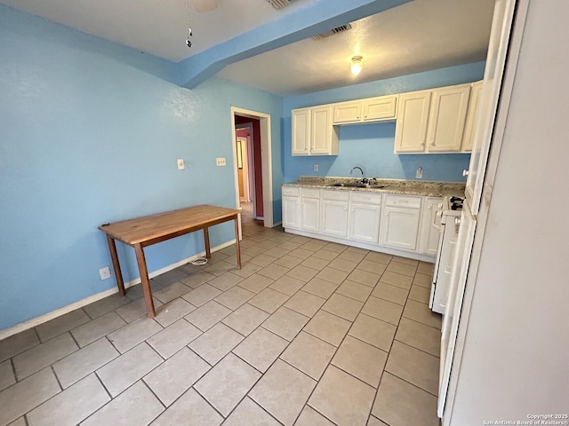 kitchen featuring sink, gas range gas stove, light tile patterned floors, light stone countertops, and white cabinets