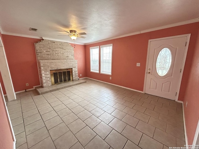 tiled foyer entrance with crown molding, a brick fireplace, and ceiling fan