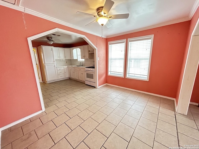 kitchen with white cabinets, backsplash, light tile patterned floors, white gas range oven, and crown molding