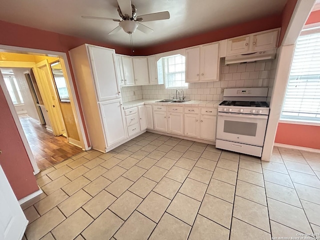 kitchen featuring white cabinetry, white gas range, sink, and backsplash