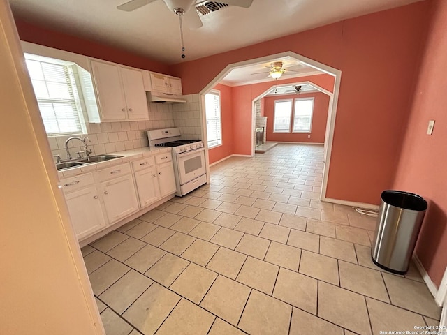 kitchen featuring white gas range, sink, white cabinets, and ceiling fan