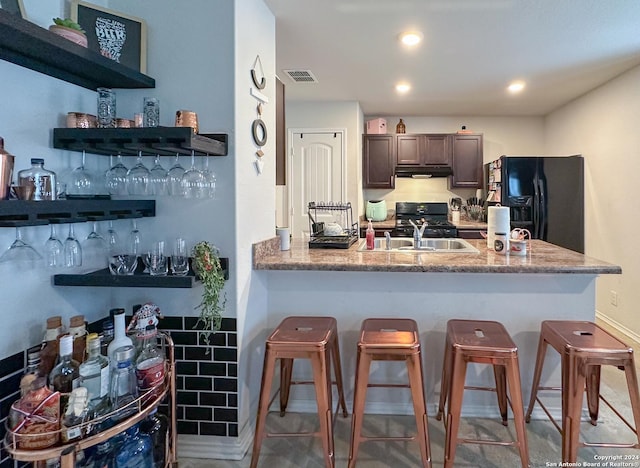 kitchen with black appliances, sink, a breakfast bar area, kitchen peninsula, and dark brown cabinets