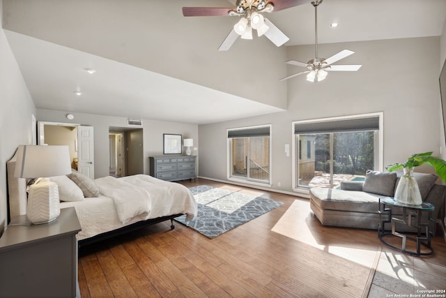 bedroom featuring a skylight, high vaulted ceiling, access to outside, ceiling fan, and hardwood / wood-style floors