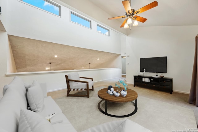 living room with ceiling fan, light colored carpet, a healthy amount of sunlight, and a towering ceiling