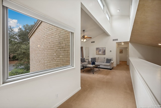 corridor featuring a towering ceiling, light carpet, and a wealth of natural light