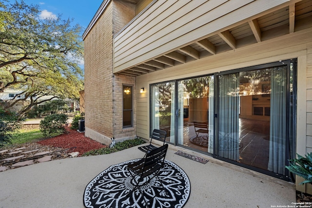 view of exterior entry featuring central AC unit and a patio area