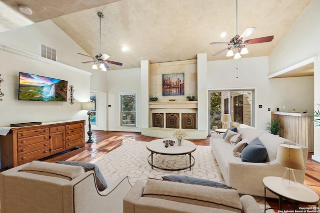 living room with ceiling fan, wood-type flooring, a fireplace, and high vaulted ceiling