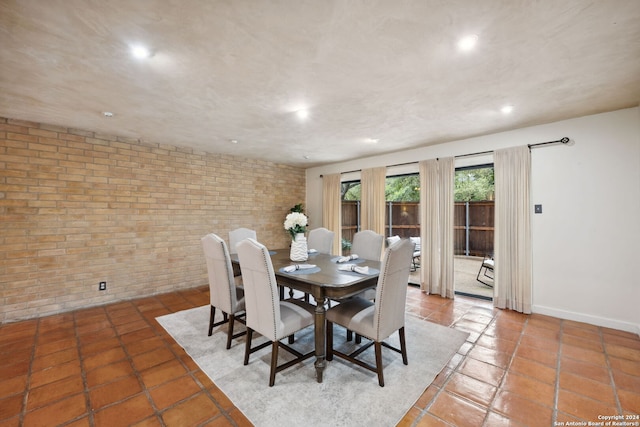 tiled dining space featuring brick wall