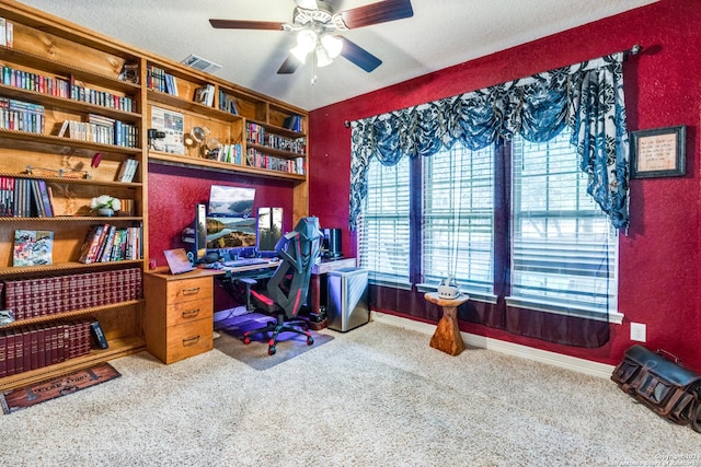 carpeted home office with a textured ceiling and ceiling fan