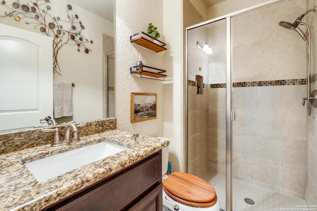 bathroom featuring vanity, a shower with shower door, and toilet