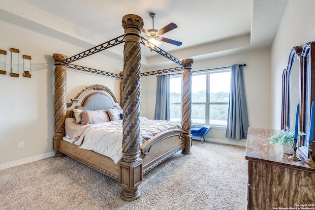 carpeted bedroom with ceiling fan and a raised ceiling