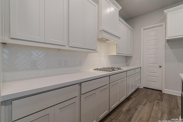 kitchen with dark wood-type flooring, tasteful backsplash, white cabinets, custom exhaust hood, and stainless steel gas stovetop