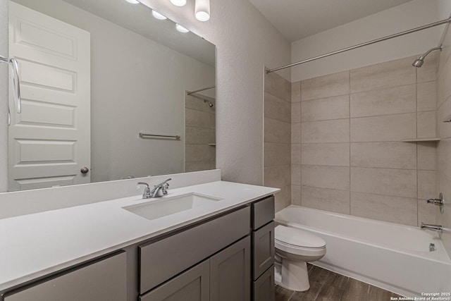 full bathroom featuring hardwood / wood-style flooring, vanity, toilet, and tiled shower / bath combo