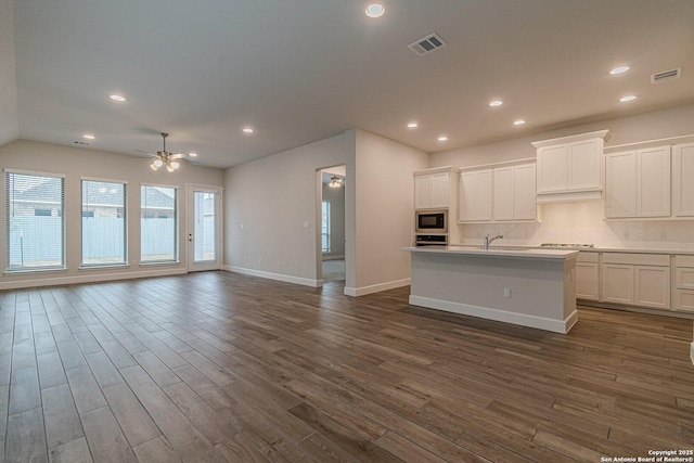 kitchen featuring built in microwave, a kitchen island with sink, white cabinets, and dark hardwood / wood-style flooring