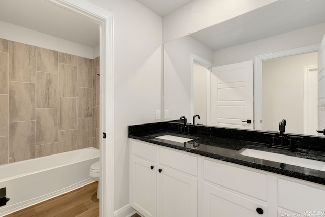 full bathroom featuring tiled shower / bath combo, wood-type flooring, vanity, and toilet