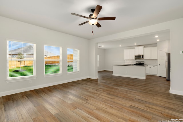 unfurnished living room featuring sink, light hardwood / wood-style floors, and ceiling fan