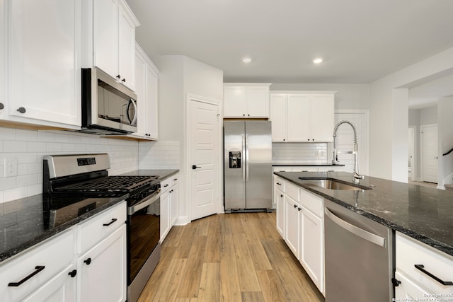 kitchen with white cabinetry, sink, stainless steel appliances, and dark stone countertops