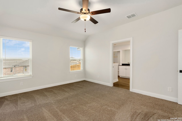 spare room with lofted ceiling, ceiling fan, and dark colored carpet