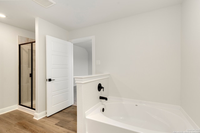 bathroom with shower with separate bathtub and wood-type flooring