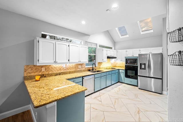 kitchen with vaulted ceiling with skylight, white cabinetry, decorative backsplash, kitchen peninsula, and stainless steel appliances