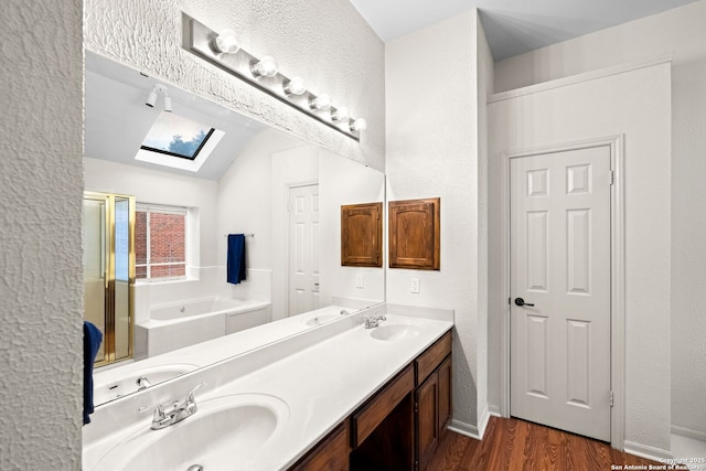 bathroom featuring vaulted ceiling with skylight, vanity, a bath, and hardwood / wood-style floors