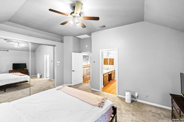 bedroom with lofted ceiling, ensuite bathroom, light colored carpet, a closet, and ceiling fan