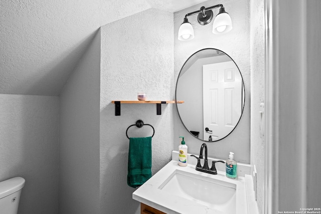 bathroom with vanity, vaulted ceiling, toilet, and a textured ceiling