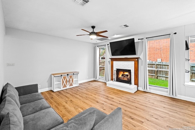 living room with ceiling fan, a fireplace, and hardwood / wood-style floors