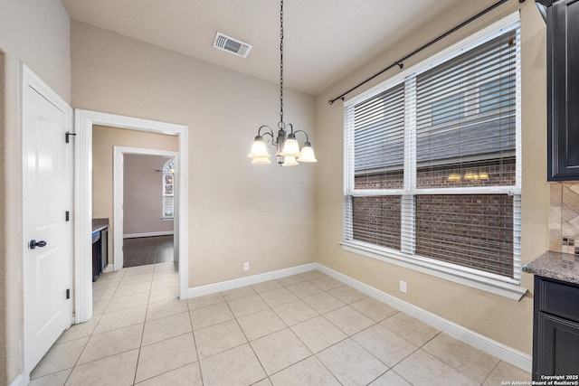 unfurnished dining area featuring light tile patterned floors and a notable chandelier