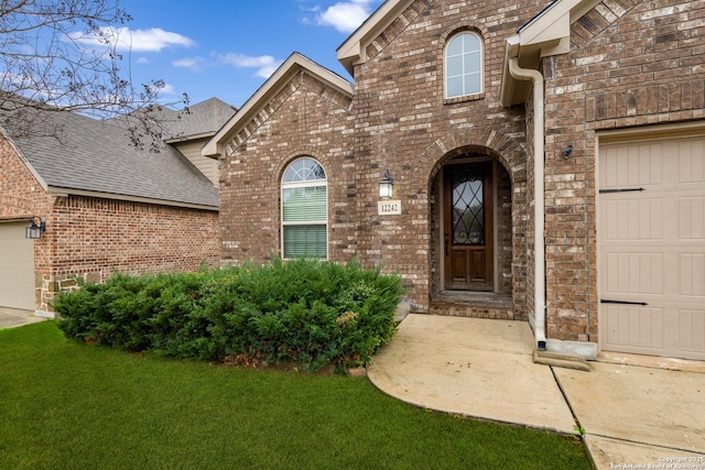 doorway to property with a garage and a lawn