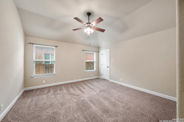 empty room with vaulted ceiling, plenty of natural light, carpet flooring, and ceiling fan