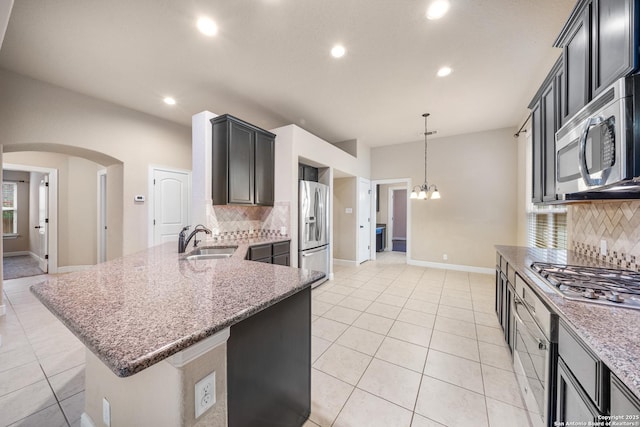 kitchen featuring sink, a notable chandelier, kitchen peninsula, stainless steel appliances, and light stone countertops