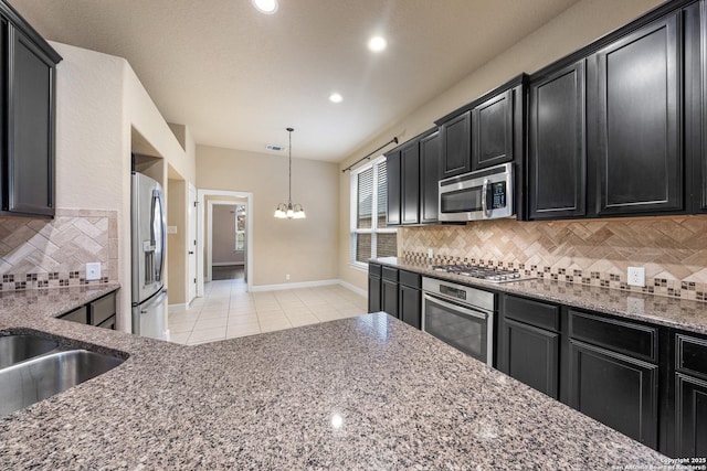 kitchen with tasteful backsplash, light stone counters, hanging light fixtures, light tile patterned floors, and stainless steel appliances