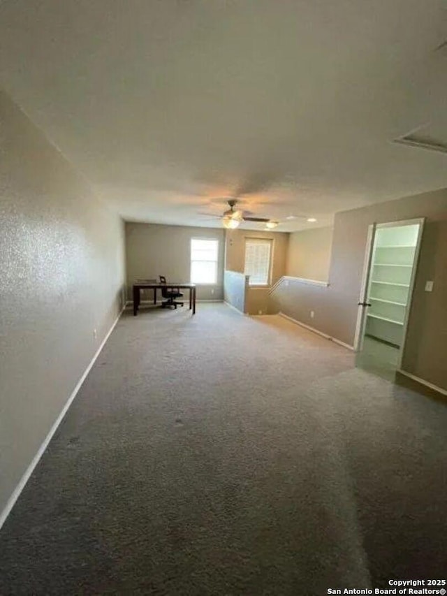 empty room featuring ceiling fan and carpet