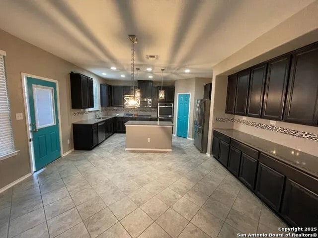 kitchen with light tile patterned floors, tasteful backsplash, hanging light fixtures, and a center island