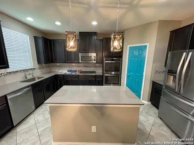 kitchen with backsplash, appliances with stainless steel finishes, a center island, and decorative light fixtures