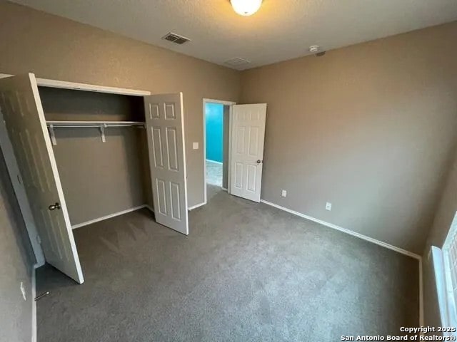 unfurnished bedroom featuring a closet and dark colored carpet