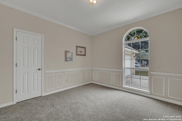 unfurnished room featuring crown molding, wainscoting, carpet flooring, and a decorative wall