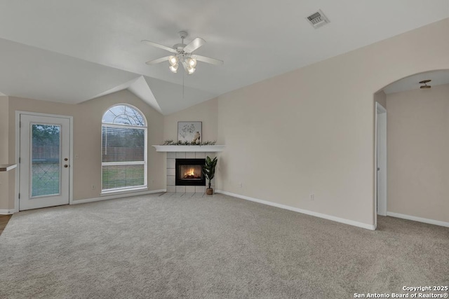 unfurnished living room with arched walkways, visible vents, light carpet, ceiling fan, and a tile fireplace