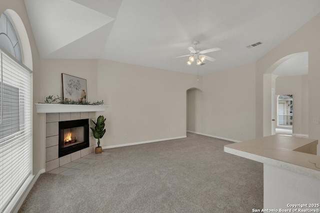 unfurnished living room featuring carpet, visible vents, vaulted ceiling, and a tile fireplace